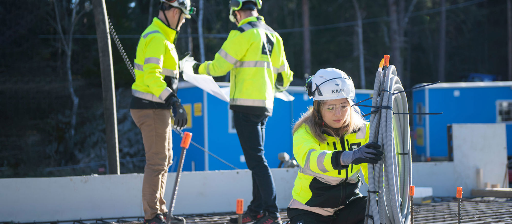 Medarbetare på Veitech arbetar med ett rör, två kollegor står i bakgrunden och tittar på en ritning.