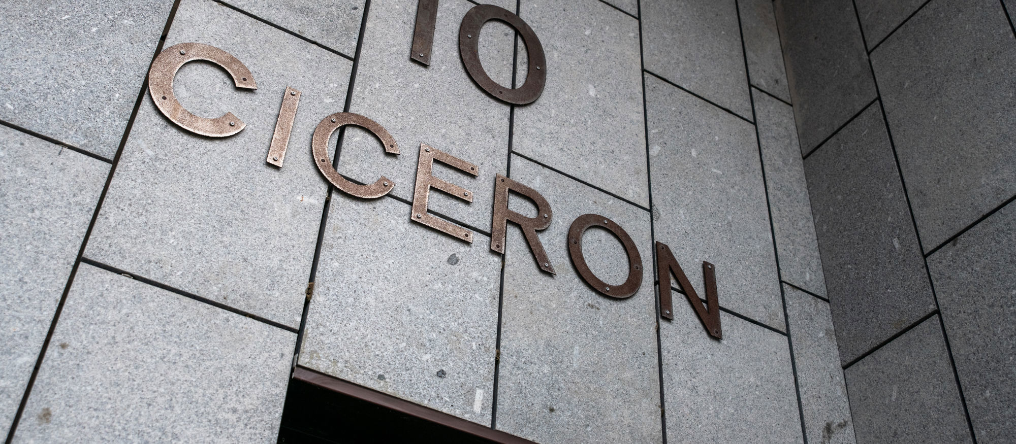 Fasadbild från Ciceron. Grå stenfasad med nummer 10 och namnet "Ciceron" i gulmetall över porten