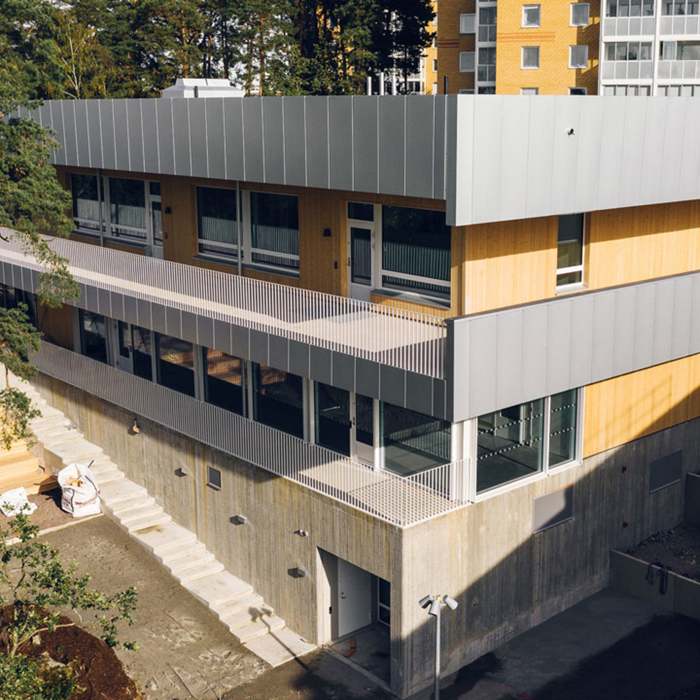 Tvåvåningsbyggnad i trä och betong med balkonger runt om
