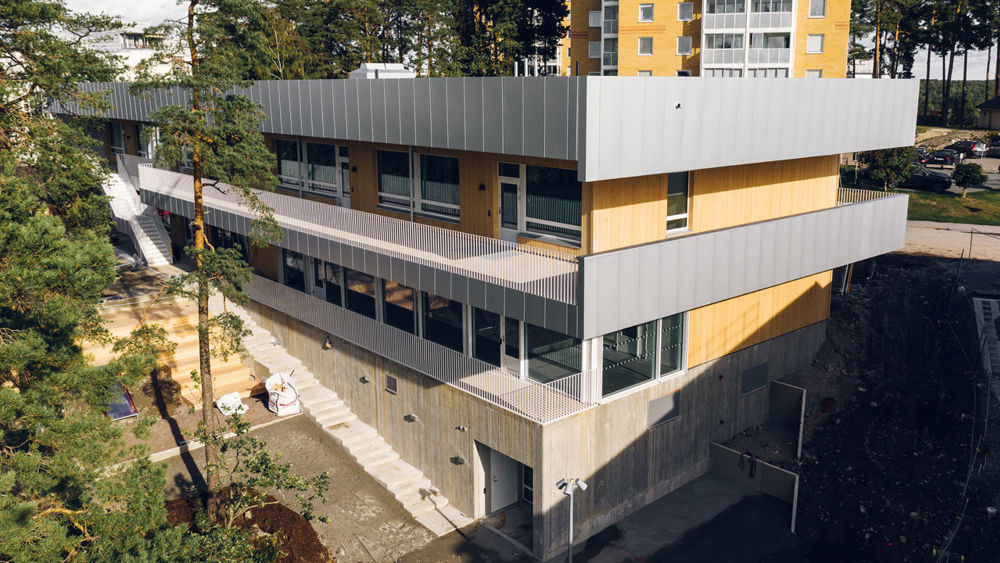 Tvåvåningsbyggnad i trä och betong med balkonger runt om